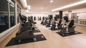 Une salle de sport équipée de plusieurs tapis de course, de vélos d’exercice et de poids.
