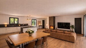 A modern kitchen with a dining area, a living room with a fireplace, and a large TV. - Luxury villa Lilly Aaron swimming pool and lake of sainte croix (Artigues)