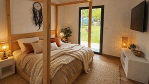 A bedroom with a four-poster bed, bedside lamps, a dreamcatcher, a television, and a view of the outdoors. - Luxury villa Lilly Aaron swimming pool and lake of sainte croix (Artigues)