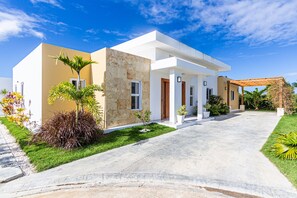 Una casa moderna de dos pisos con entrada para coches, un porche cubierto y jardines bien cuidados.