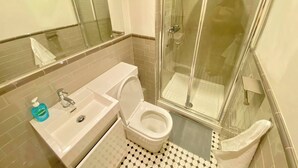 Un bagno con il water, lavandino e doccia.