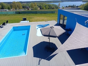 A swimming pool with a deck, lounge chairs, and a covered seating area. - Domek nr 1 "Błękitne Wzgórze" (Żałe)