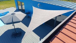 Ein modernes Gebäude mit blauer Fassade, einer Terrasse mit Tisch und Stühlen sowie einem großen Fenster.