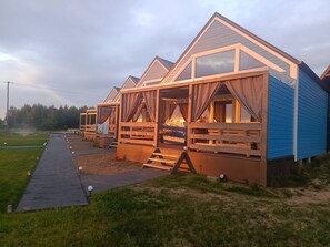 A row of wooden cabins with large windows and a covered porch area.