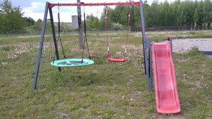 Ein Spielplatz mit Schaukeln und einer Rutsche.