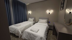 Ein Hotelzimmer mit zwei Betten, einem Schreibtisch, einem Nachttisch und einer Wandleuchte.