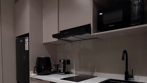 Eine kleine Küche mit Kühlschrank, Waschmaschine, Kaffeemaschine und Mikrowelle.