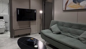 Ein modernes Wohnzimmer mit Flachbildfernseher, einer Couch, einem Couchtisch und einem Bild an der Wand.