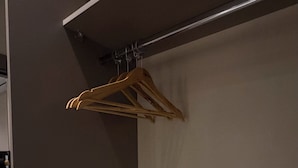 Ein Zimmer mit Kleiderschrank, Kleiderstange und Ablagefläche.