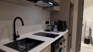 Cocina compacta con microondas, lavaplatos, cafetera y lavadora.
