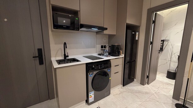 Cocina compacta con microondas, cafetera y lavadora.