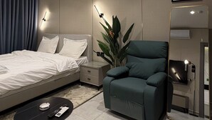 Habitación de hotel moderna con cama, sofá, una mesita, una planta y un espejo.