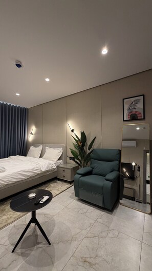 Een moderne hotelkamer met een bed, een bank, een tafeltje, een plant en een spiegel.
