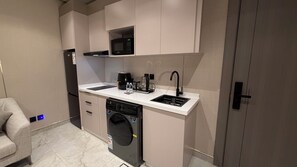 A compact kitchen with a dishwasher, a coffee maker, a microwave, and a sink.