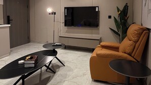 A modern living room with a flat-screen TV, a sofa, a coffee table, and a floor lamp. - 009 tara-JRE Jabal Al Lweibdeh with stunning view (Amman)