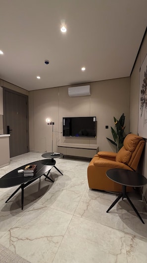 A modern living room with a flat-screen TV, a sofa, a coffee table, and a floor lamp. - 009 tara-JRE Jabal Al Lweibdeh with stunning view (Amman)