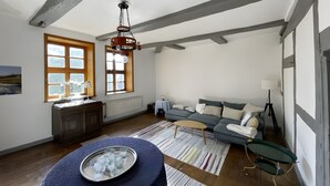 A room with a wooden ceiling, a sofa, a table with a tray of glasses, and a window with a view. - Apartment 'Alter Weserhof Forst' with Private Garden and Balcony (Bevern)