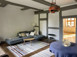 A modern living room with a grey sofa, a small round table, a patterned rug, and a hanging light fixture. - Apartment 'Alter Weserhof Forst' with Private Garden and Balcony (Bevern)