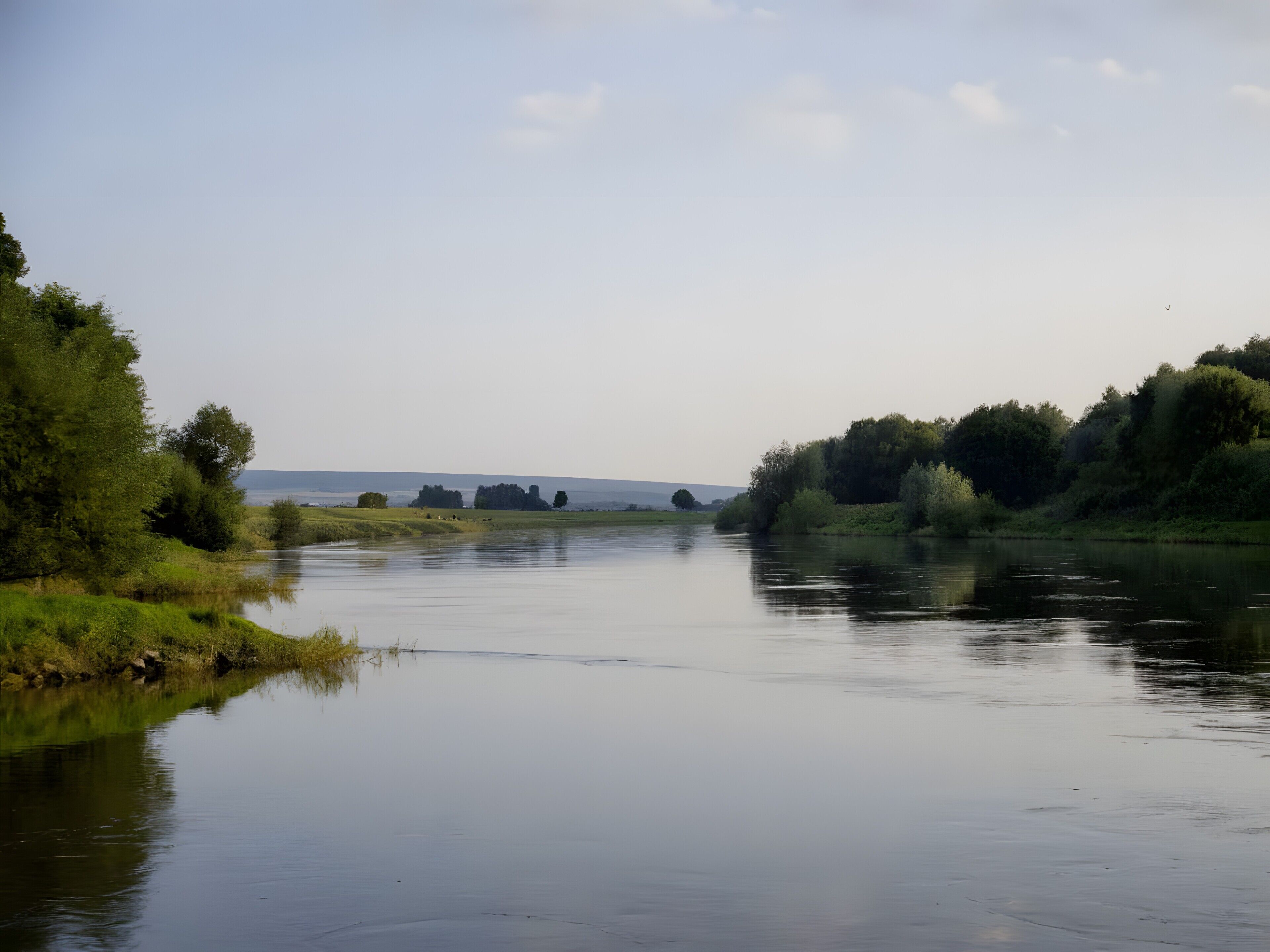 Une rivière paisible, bordée d’arbres des deux côtés.