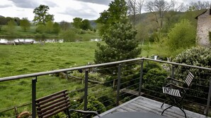 A terrace with a bench and a table, overlooking a grassy area with trees and a body of water. - Apartment 'Alter Weserhof Forst' with Private Garden and Balcony (Bevern)