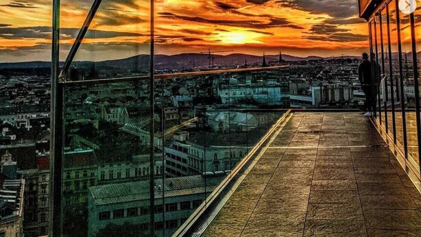 A high-rise building with a glass facade overlooking a cityscape during sunset. - Vienna ROOF TOP Terrace APT (Wien)