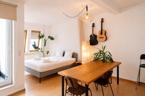 Ein modernes Schlafzimmer mit Bett, Nachttisch und einem Essbereich mit Stühlen.