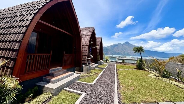 A modern building with a curved roof, a gravel pathway, and a mountain view. - Arkatama Lumbung Bali (Kintamani)