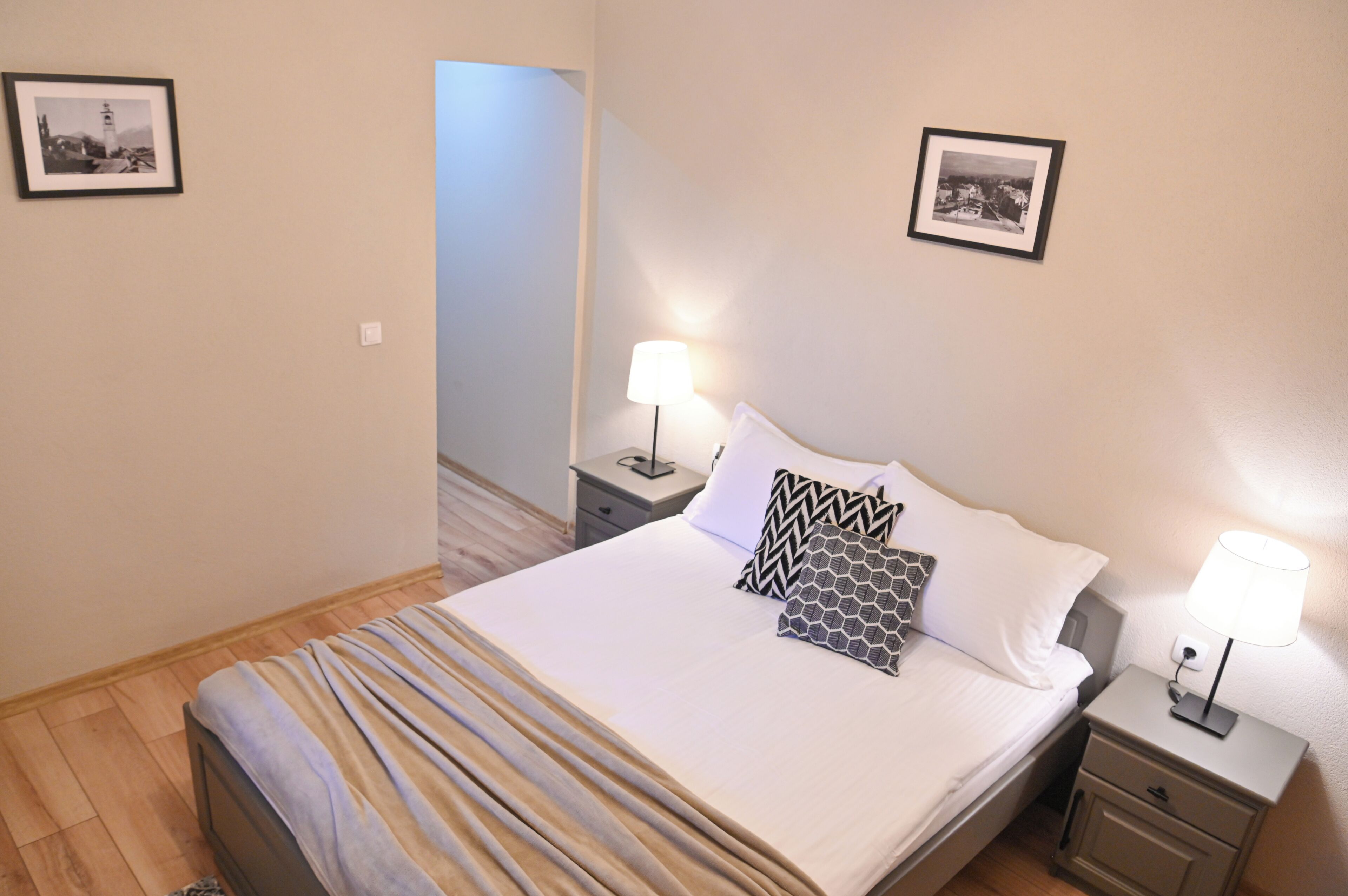 Un letto rifatto con cuscini decorati, una lampada da comodino e un quadro appeso alla parete.