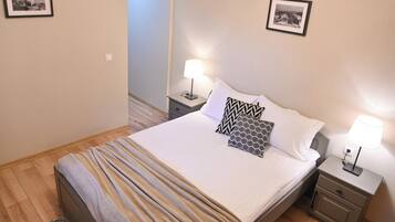 Un letto rifatto con cuscini decorati, una lampada da comodino e un quadro appeso alla parete.