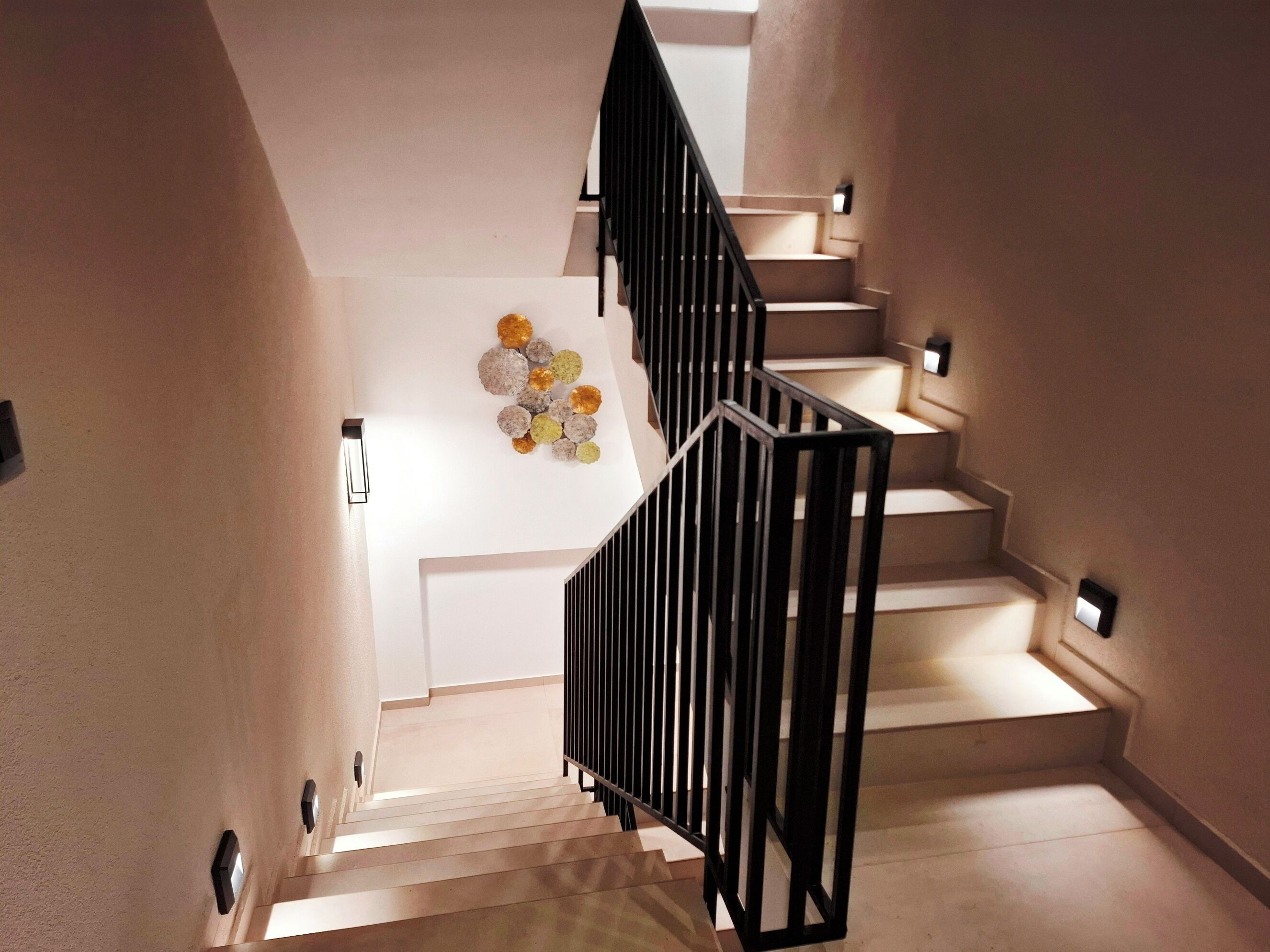 A staircase with a modern design, featuring a black railing and light-colored walls.