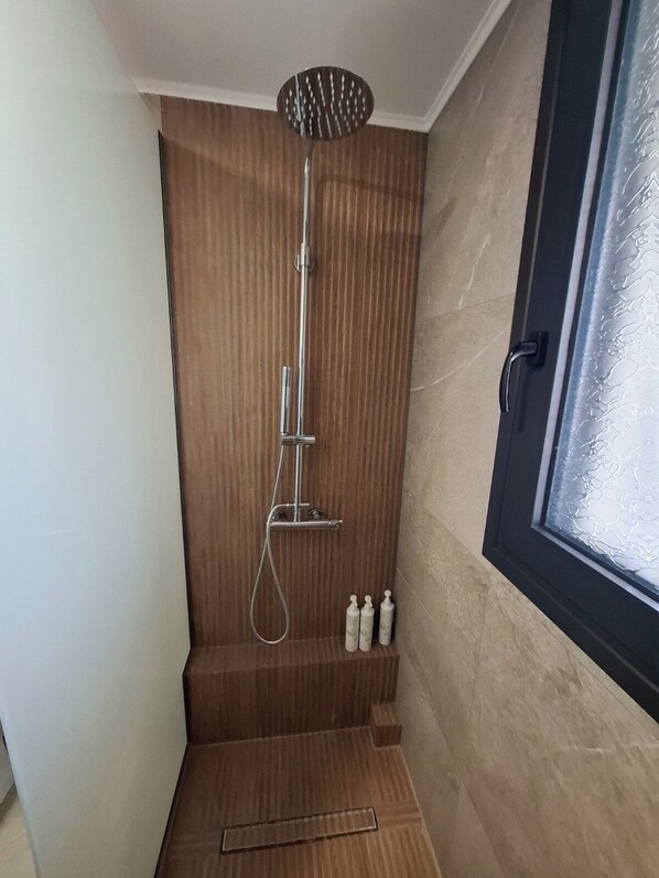 A shower with a handheld showerhead, a handheld shower attachment, and a handheld scrubber. - Aelia Luxury Apartments & Pool (Skafidia)