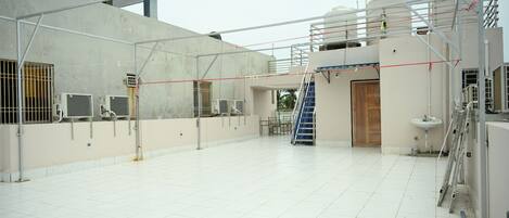 A spacious indoor area with a tiled floor, a staircase, and a door leading to another room.