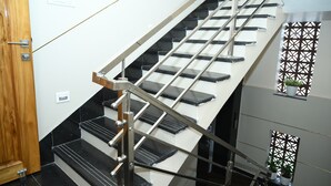 Μια σκάλα με μεταλλικό κάγκελο, ασπρόμαυρα σκαλοπάτια και μια ξύλινη πόρτα στην αριστερή πλευρά.
