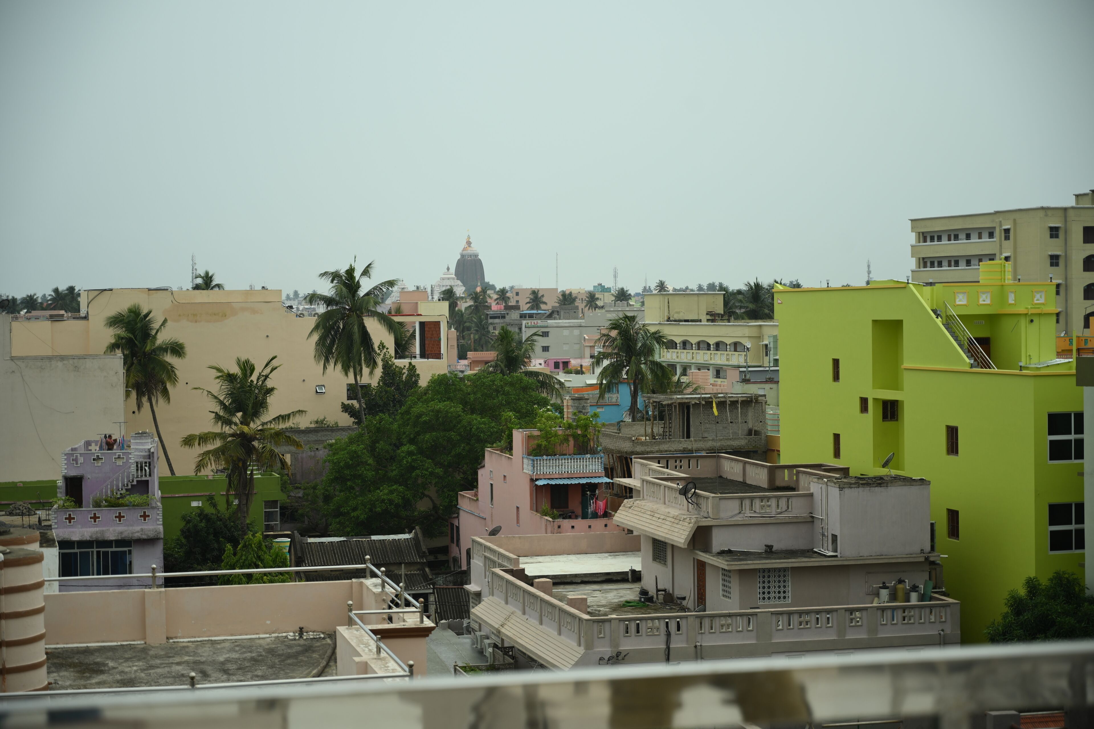 A cityscape with multi-story buildings, some with balconies, and a prominent dome structure in the distance.