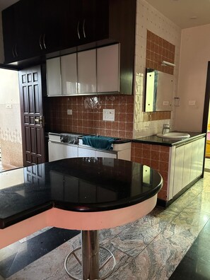 A modern kitchen with a black countertop, stainless steel appliances, and a tiled backsplash. - Marvelous 3-bedroom apartment with AC in vibrant Chennai (Chennai)
