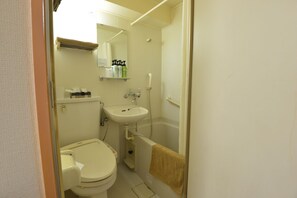 Une petite salle de bain avec des toilettes, un lavabo et une douche.