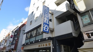 Un hôtel à plusieurs étages, reconnaissable à son grand panneau bleu, avec un escalier menant à l’entrée et un ciel bleu clair en arrière-plan.