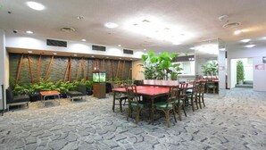 Un vaste espace intérieur doté d’un sol en pierre, de nombreuses tables et chaises, ainsi que de plantes en pot.