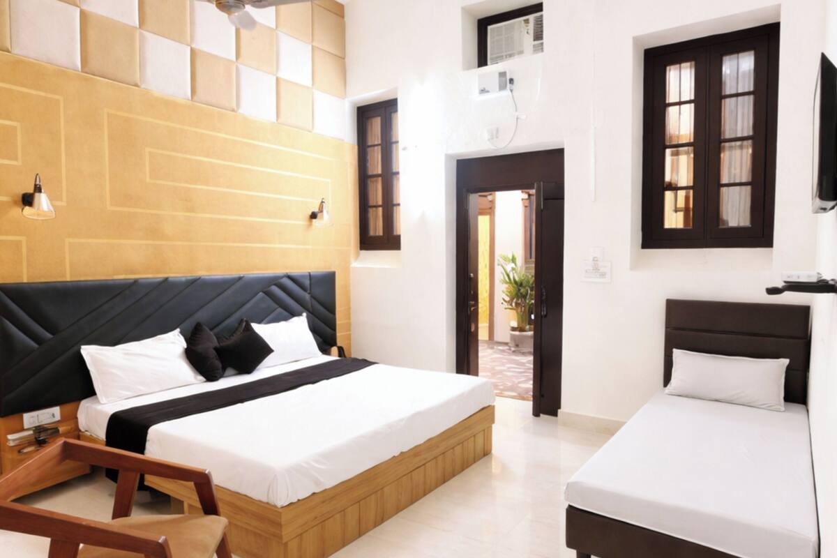 Een hotelkamer met een groot bed, een kleiner bed, een bureau en een plafondventilator.