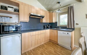 A compact kitchen with wooden cabinets, a microwave, a coffee maker, and a dishwasher.