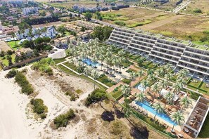 Ein Resort mit mehrstöckigen Gebäuden, einem Schwimmbad und Palmen.