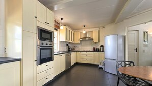A kitchen with white cabinets, a double oven, a refrigerator, and a dining area with a table and chairs. - Nice home in Rendeux with WiFi (Rendeux)