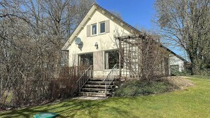 A two-story house with a staircase leading to the entrance, surrounded by trees and a grassy area. - Nice home in Rendeux with WiFi (Rendeux)
