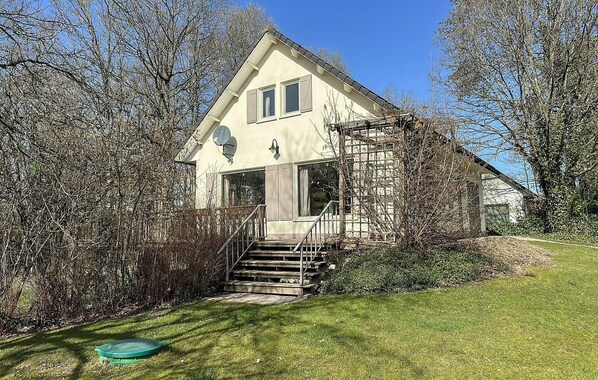 A two-story house with a staircase leading to the entrance, surrounded by trees and a grassy area. - Nice home in Rendeux with WiFi (Rendeux)