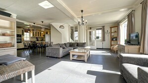 A modern living room with a sectional sofa, a coffee table, and a dining area with chairs and a table. - Nice home in Rendeux with WiFi (Rendeux)