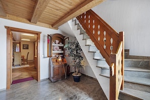 A wooden staircase with a railing, a potted plant, a wooden cabinet with decorative items, and a dining area with a table and chairs. - Apartment "Leo" with Private Terrace, Shared Garden, and Wi-Fi (Missen-Wilhams)