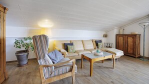 Un salon comprenant un canapé, un fauteuil, une table basse en bois, une plante en pot et un meuble.