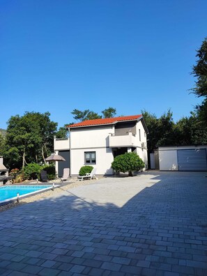 A modern two-story house with a swimming pool, outdoor seating, and a garage.