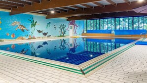 An indoor swimming pool with a mural of sea life, a blue pool edge, and a view of trees through large windows. - Scenic Lakeview Cottage for 6 (Ewijk)