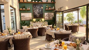 Un ristorante con mobili in vimini, un ricco buffet per la colazione e opere d'arte alle pareti.